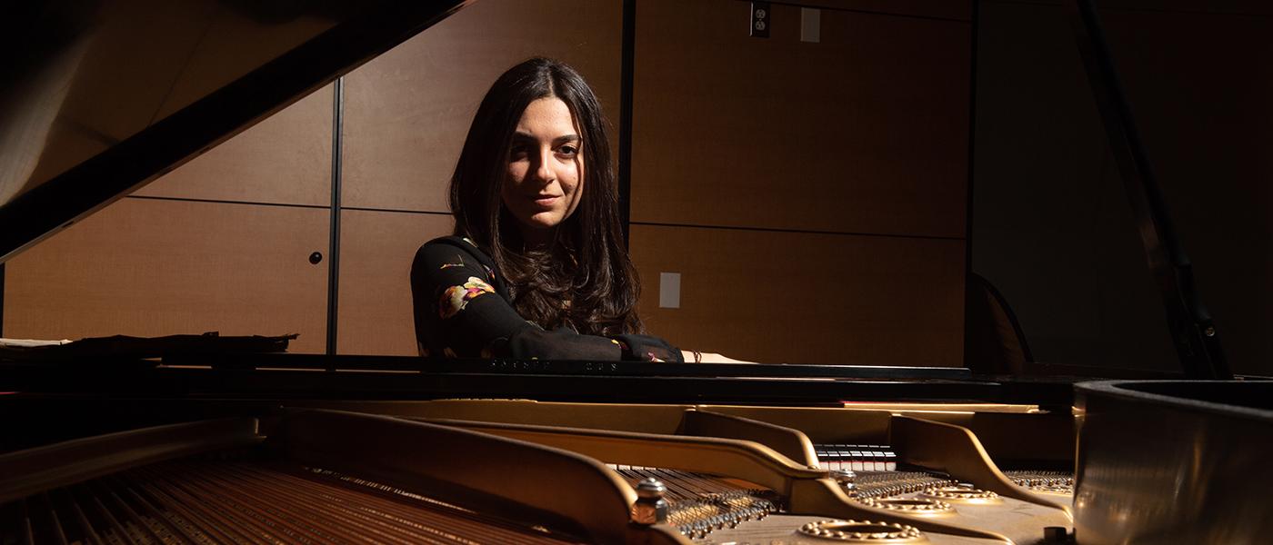 Lady standing behind an open piano