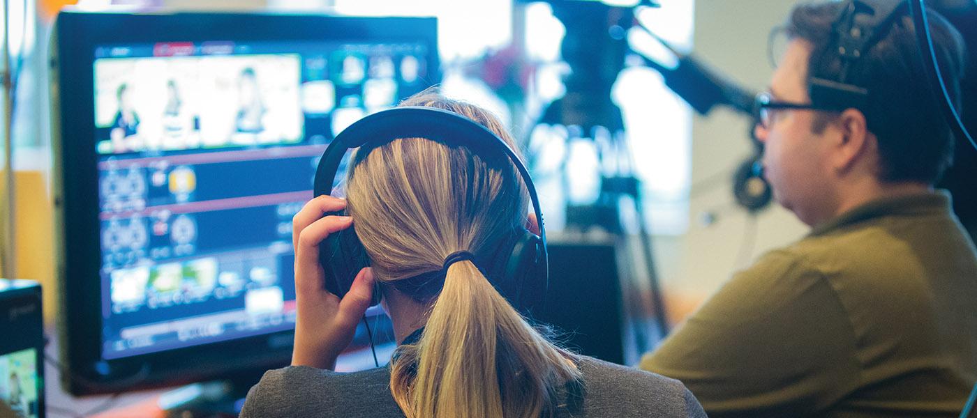 Over the shoulder view of two communication arts students in the studio working on a broadcast